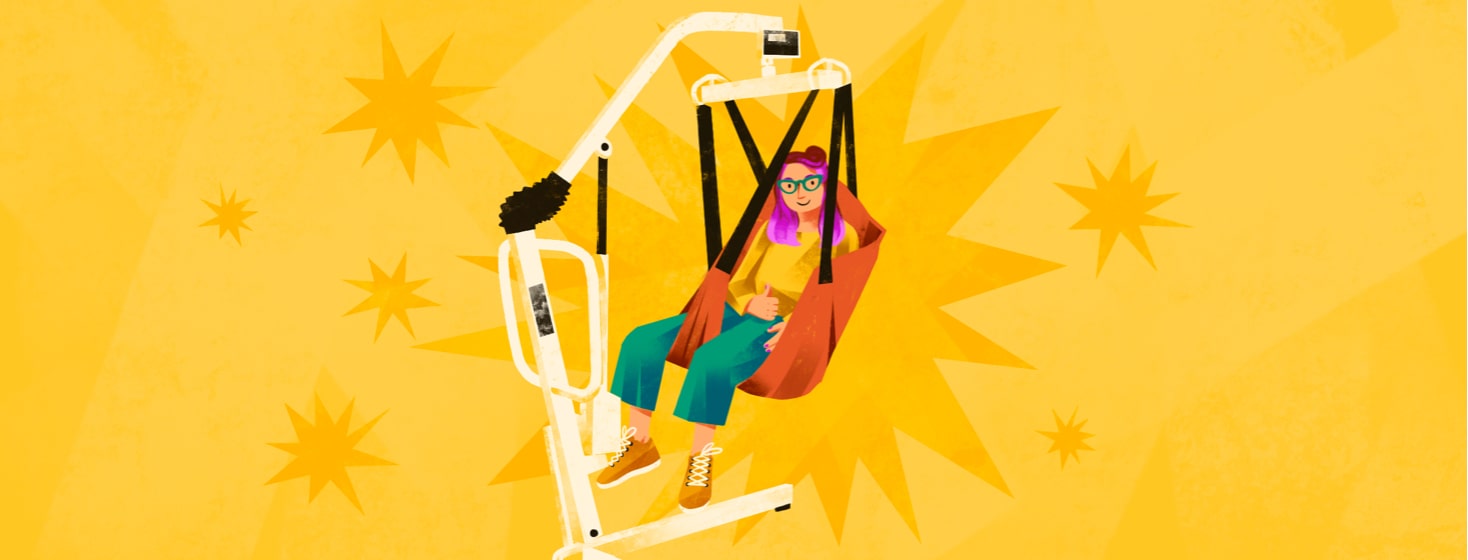 alt=a woman gives a thumbs up from the sling of a patient lift.