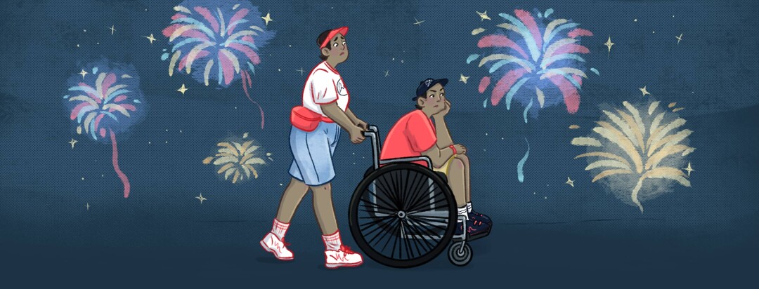 A woman pushes her teenage son in a wheelchair as fireworks explode in the distance